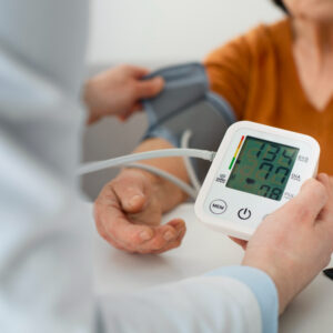 Ein Bildausschnitt, auf dem zusehen ist, wie eine medizinische Fachperson einer anderen den Blutdruck misst.