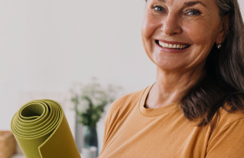 Lächelnde ältere Frau mit Yoga-Matte in der Hand