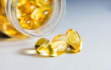 Omega3 Kapseln die aus einer geöffneten Flasche rausgepurzelt sind