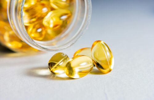 Omega3 Kapseln die aus einer geöffneten Flasche rausgepurzelt sind