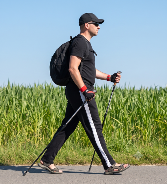 mann läuft entlang eines feldes mit nordic walking stöcken