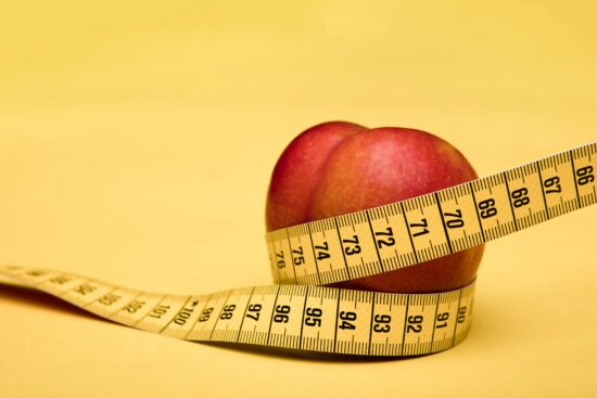 Ein Apfel wird von einem Maßband umschlungen