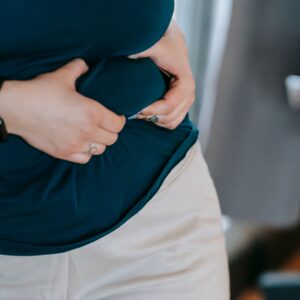Frau kneift sich in den Bauch