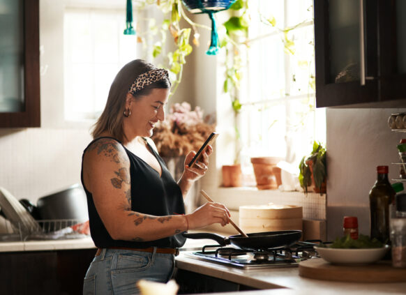 Woman cooking a meal from a recipe on her phone