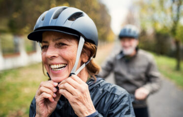 Happy, healthy woman adjusting her bike helmet while out on a cycle