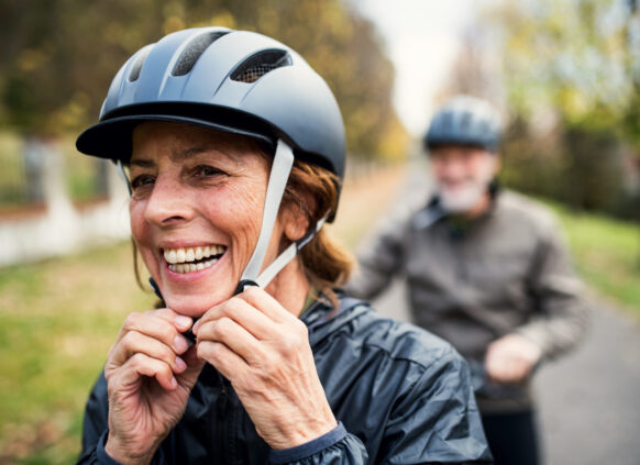 Happy, healthy woman adjusting her bike helmet while out on a cycle