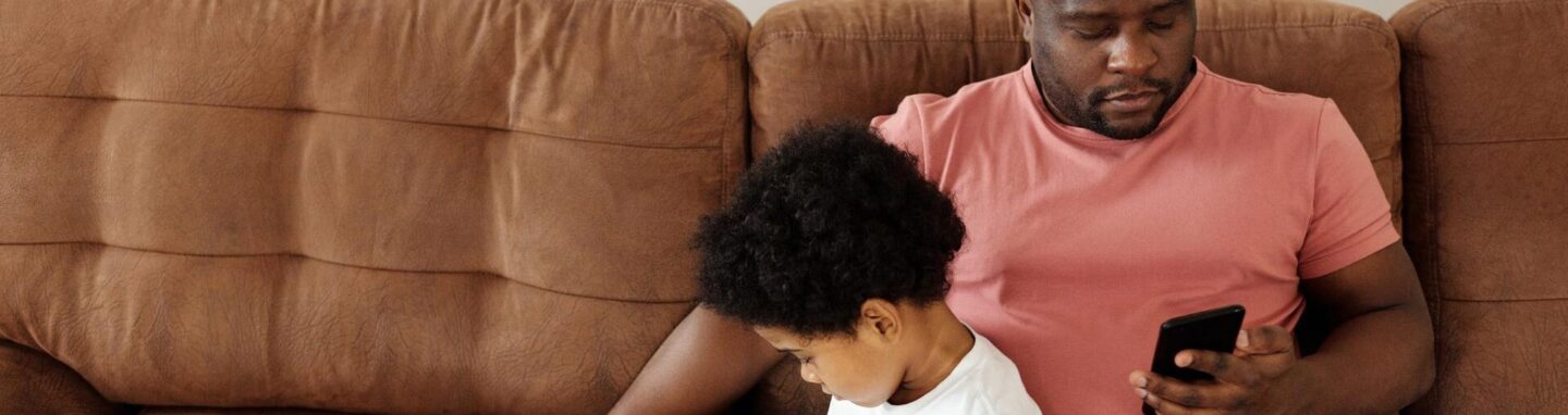 Man with son on the sofa on his phone