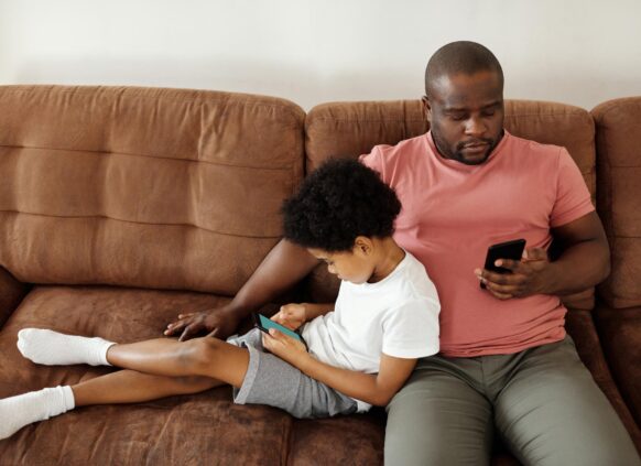 Man with son on the sofa on his phone