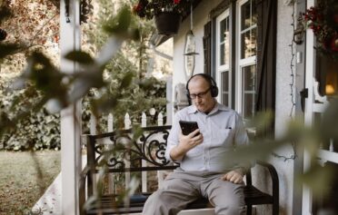 Older man on his phone sat on his porch