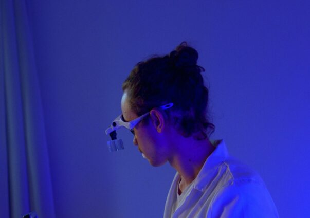 Healthcare professional analyzing medical samples under blue laboratory lighting.