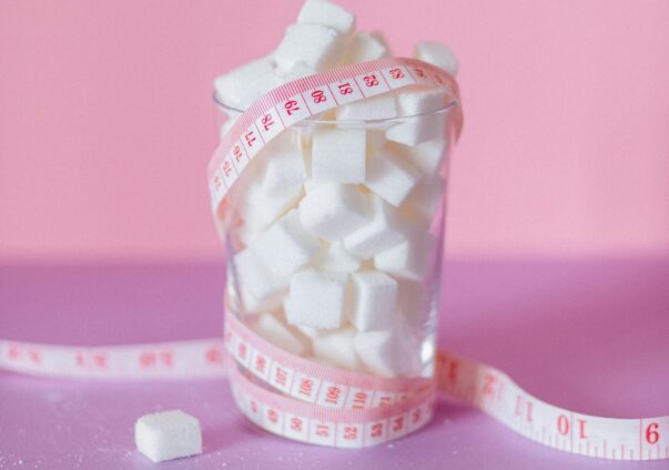 Glass filled with sugar cubes wrapped in a measuring tape, symbolizing insulin resistance and health concerns.