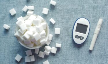 Blood glucose meter, lancet device, and sugar cubes symbolizing insulin resistance and diabetes risk.