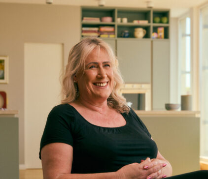 Smiling woman sitting on a chair in a modern kitchen setting.