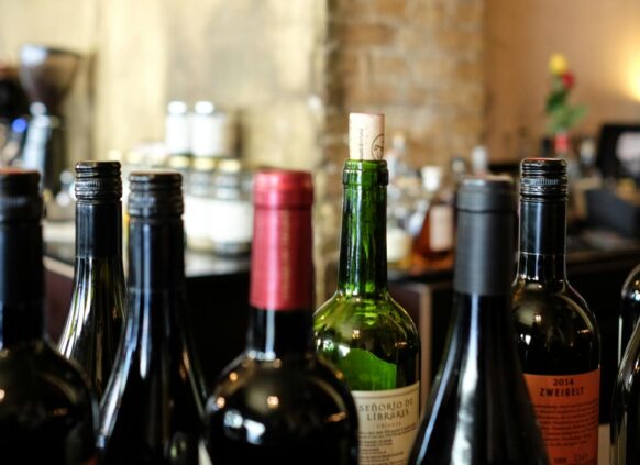 Assorted wine bottles on a bar counter with corks and screw caps.
