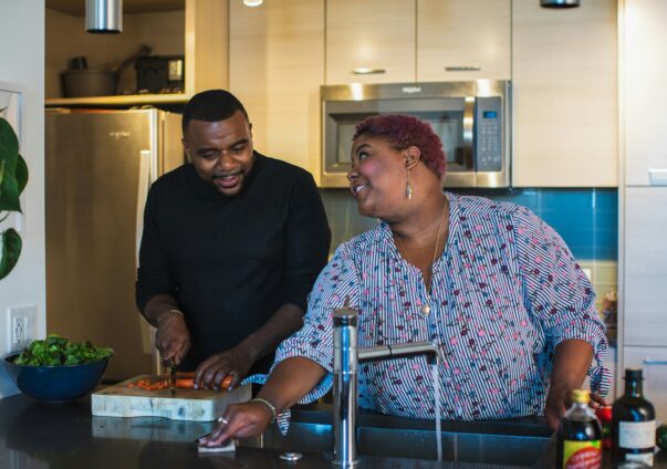 Plus-size couple preparing a healthy meal together in a home kitchen, smiling and enjoying each other's company.