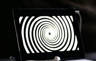 Tablet displaying hypnotic spiral pattern with earphones in front.