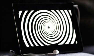 Tablet displaying hypnotic spiral pattern with earphones in front.