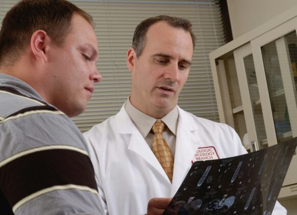 Doctor in a white coat discussing a medical scan with a male patient in a clinical setting