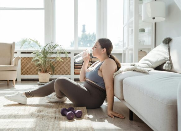 Woman resting after home workout with dumbbells and water bottle