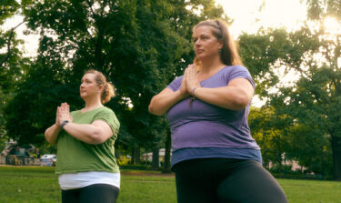 Two women doing yoga on the grass in a park