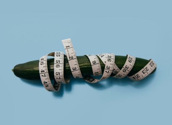 Cucumber wrapped with a white measuring tape on blue background