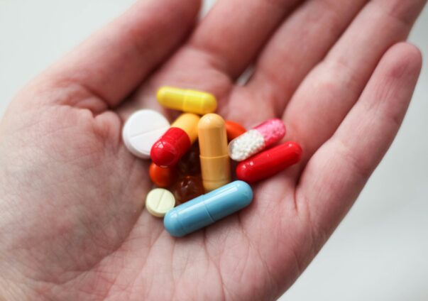 Hand holding a variety of colorful weight loss pills and capsules.