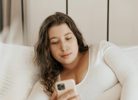 women laying on the sofa and looking at her phone