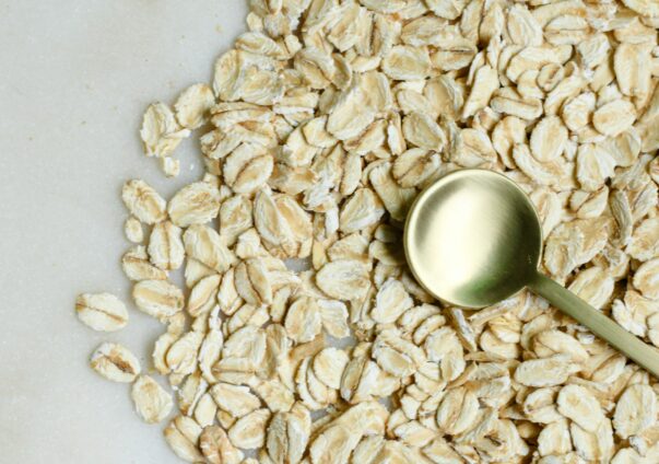 Raw rolled oats with a golden spoon on a light background