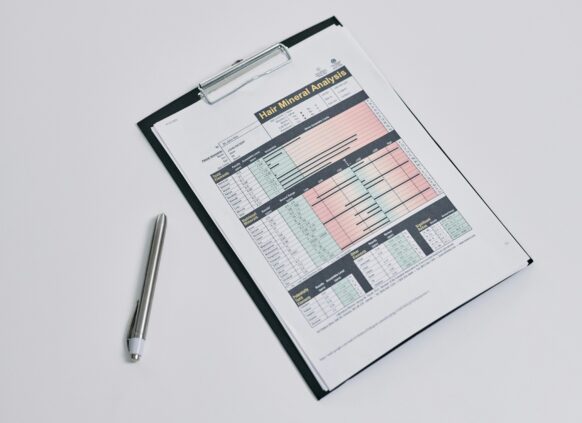 Hair mineral analysis report on clipboard with pen on white background