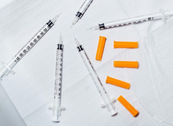 Insulin-style syringes with orange caps on medical paper surface