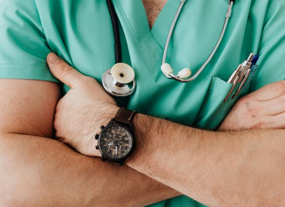 Close-up of doctor in green scrubs with stethoscope and crossed arms