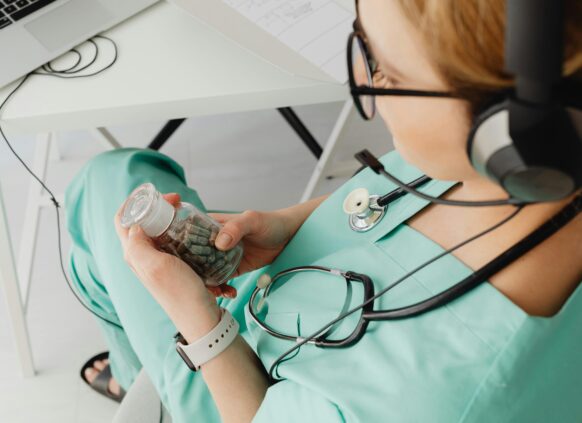 Healthcare professional examining a jar of weight loss capsules during a teleconsultation.