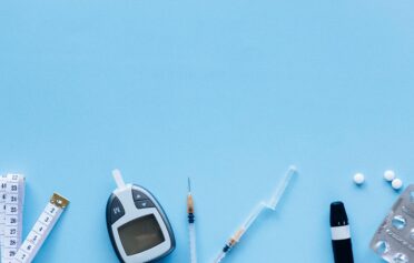 Medical tools for diabetes management including glucometer, syringe, pills, and measuring tape on blue background.