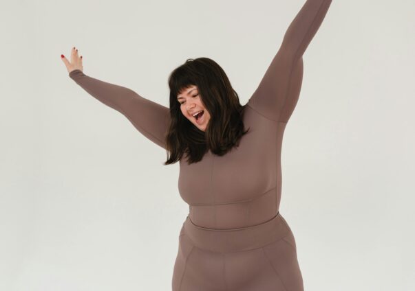 Happy plus-size woman in activewear celebrating with arms raised
