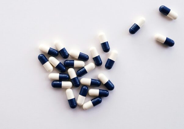 Blue and white medical capsules scattered on a white surface
