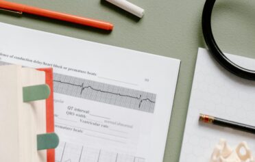 Medical study desk with open books, ECG graph, and stethoscope.