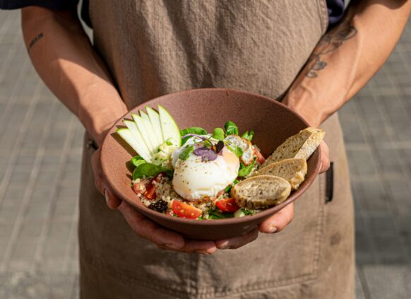 Healthy bowl with poached egg, quinoa, apple slices, tomatoes, greens, and whole grain bread