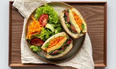 Vegetarian sandwich with fresh vegetables and salad on a wooden tray
