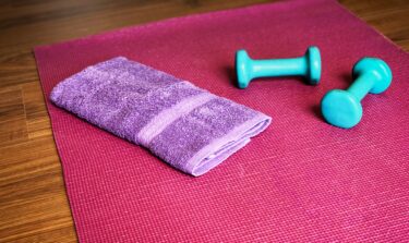 Purple towel and teal dumbbells on a red yoga mat.