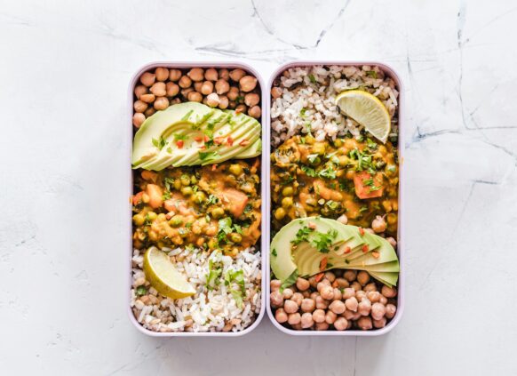Healthy vegan meal prep with chickpeas, avocado, rice, and vegetable curry in lunchboxes