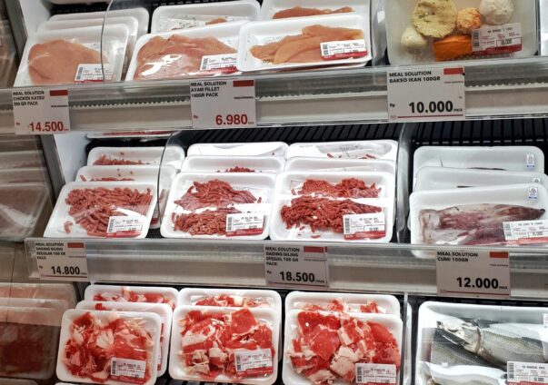 Supermarket meat section displaying packaged beef, chicken, fish, and seafood with price tags