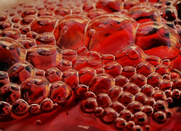 Close-up view of red liquid with bubbles symbolizing blood and high cholesterol