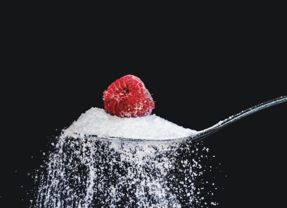 Teaspoon overflowing with sugar, with a raspberry on the top