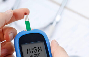 Hand holding a blood glucose test, measuring blood sugar