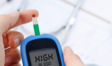 Hand holding a blood glucose test, measuring blood sugar