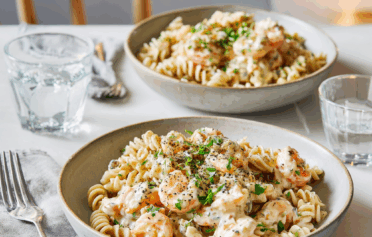 Two bowls of lentil pasta coated in prawn and cream cheese sauce