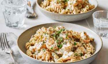 Two bowls of lentil pasta coated in prawn and cream cheese sauce