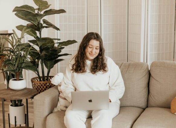 Happy, plus-sized woman on the sofa with her laptop