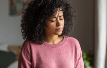 A woman with an expression of pain, holding her stomach