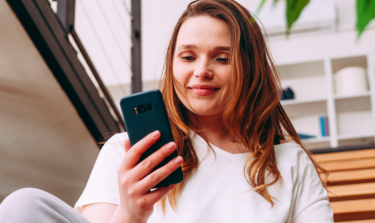 Young woman smiling and looking at her phone